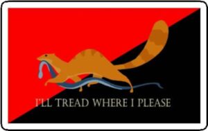 A mongoose makes off with a dead snake across the ancom red and black flag "I'll tread where I please"